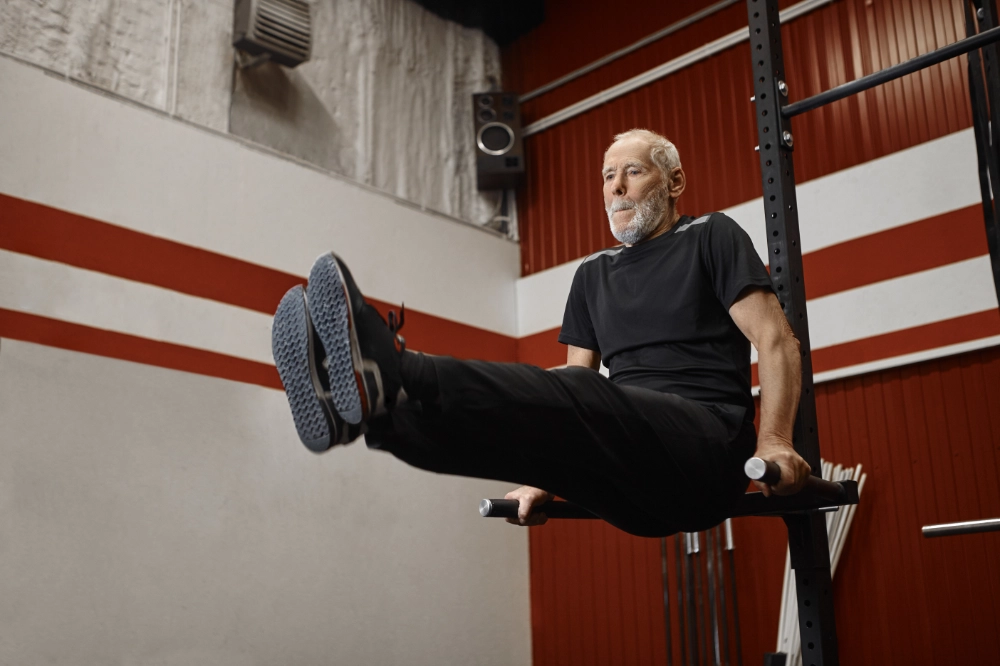 A senior doing leg raises exercise in a gym