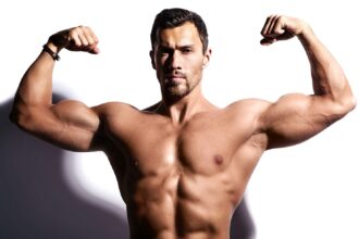 Man flexing front double biceps in gym, demonstrating exercises to increase testosterone naturally.
