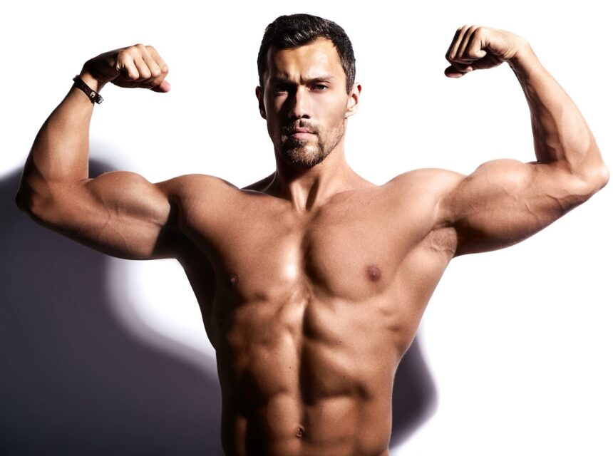 Man flexing front double biceps in gym, demonstrating exercises to increase testosterone naturally.