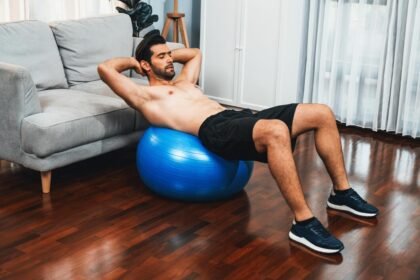 Athletic man doing abdominal crunches on a medicine ball in his Dubai Apartment
