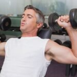 Mature man doing dumbbells shoulder military press in a gym in Dubai