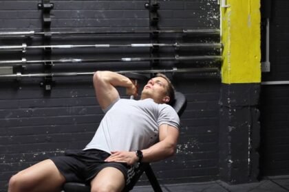 A young fit man doing a one arm dumbbell tricep extension