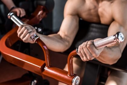 Muscular man doing machine preacher curl in a gym in Dubai