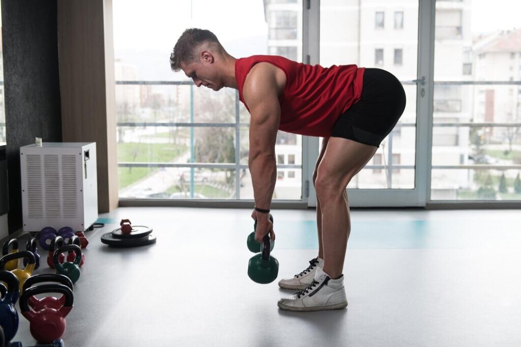 A focused athlete performing a single-arm dumbbell row in a modern Dubai gym, demonstrating the form for maximum back thickness.