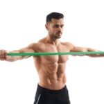 bodybuilder doing shrug exercise with resistance band.