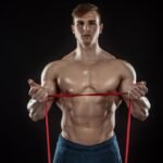 A fit young man doing bicep curls with resistance bands in Dubai