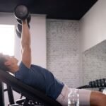 A young man doing dumbbell chest press in the gym