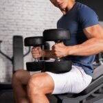 A fit young man in a gym doing seated bicep curls