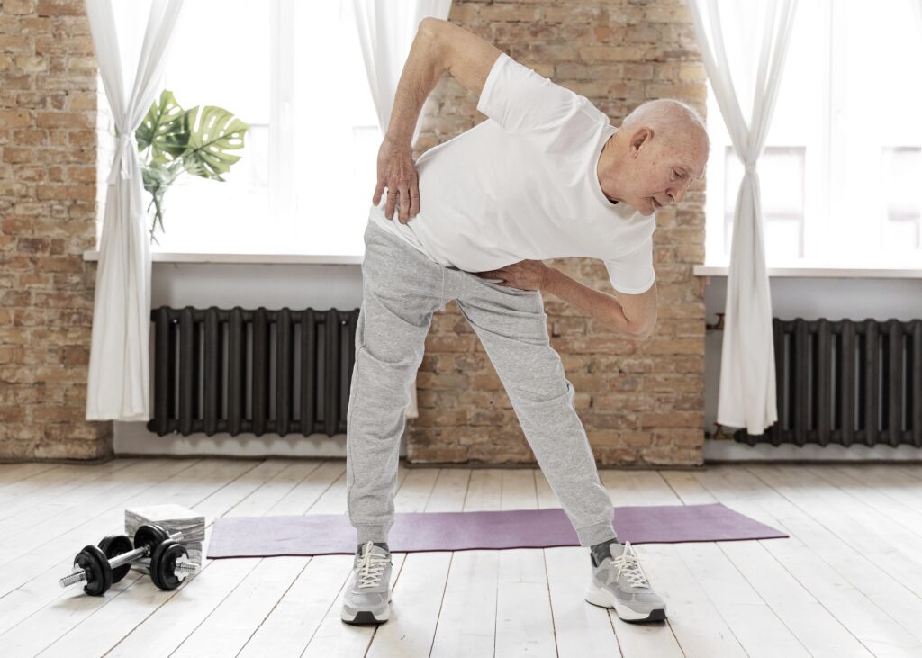 A senior man performing a gentle, joint-friendly exercise indoors, demonstrating safe movement for arthritis management.