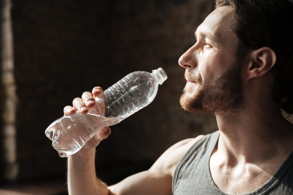 A focused athlete in a gym taking a strategic drink of water during his training session.