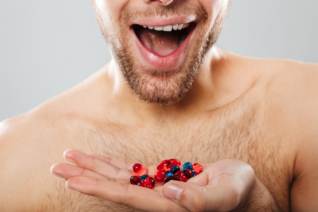 A man's hands holding men's health  supplements. Vitamin D, Zinc, and Magnesium against a clean, scientific background.