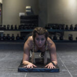 A determined female athlete holding a perfect plank position in a modern Dubai gym, demonstrating core strength and mental focus.