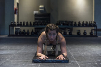 A determined female athlete holding a perfect plank position in a modern Dubai gym, demonstrating core strength and mental focus.