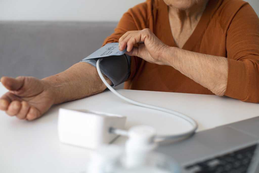 A senior woman at home monitoring her blood pressure with a digital cuff, a key practice for managing heart health.