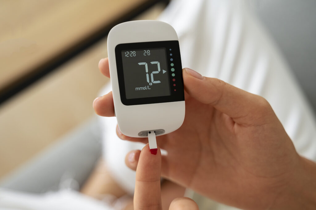 Close-up of a woman's hand using a blood glucose meter to check her blood sugar level before exercise.